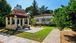A garden with a pergola, a patio, and a house with a tiled roof. - Casa San Rafael (Navajas)
