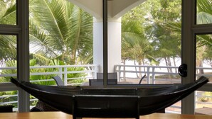 A hammock on a wooden deck with a view of palm trees through large windows. - Villa Beach Palm Cove (Clifton Beach)