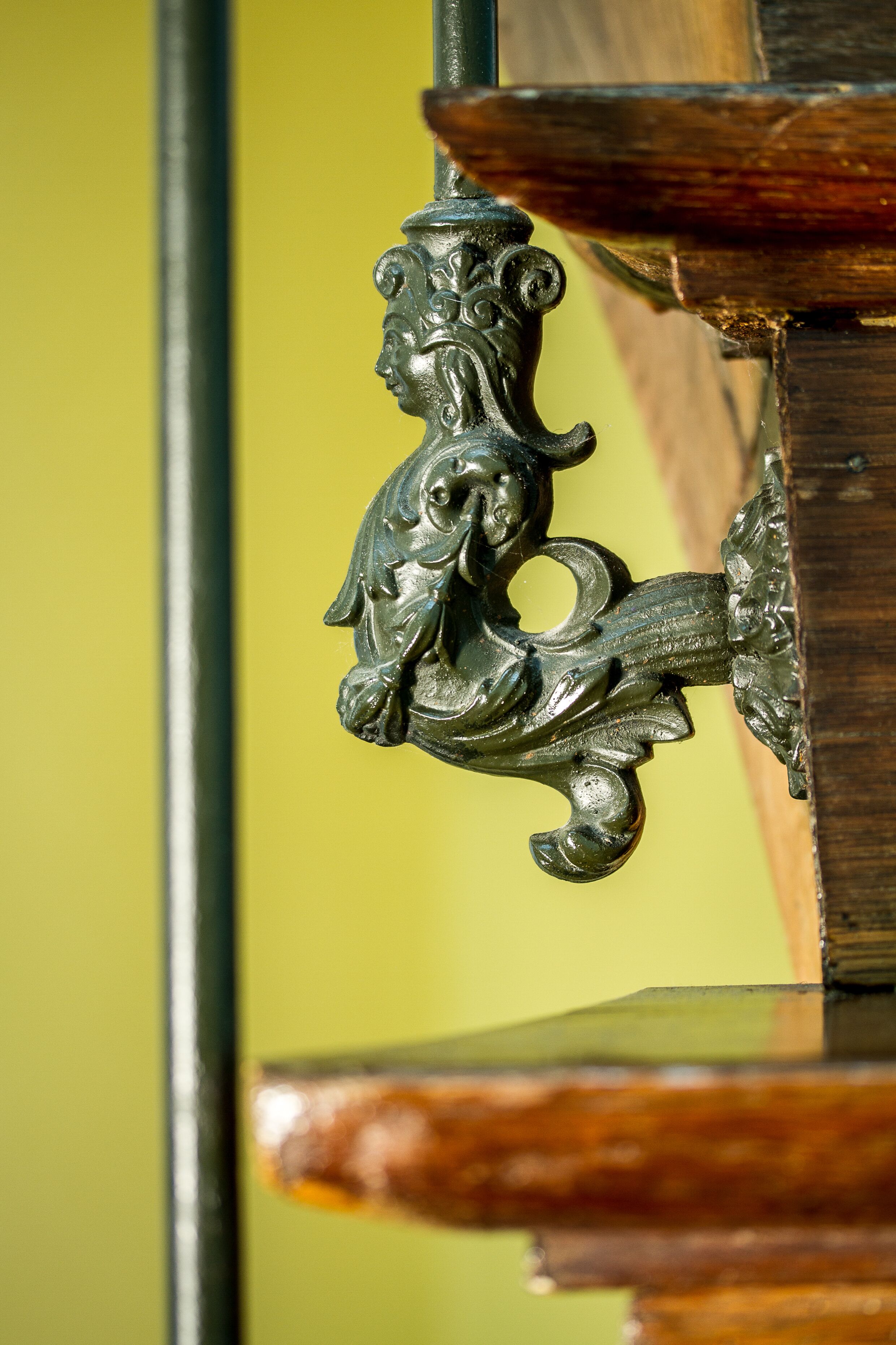 A close-up of a metal fixture with a lion's head design, attached to a wooden structure.