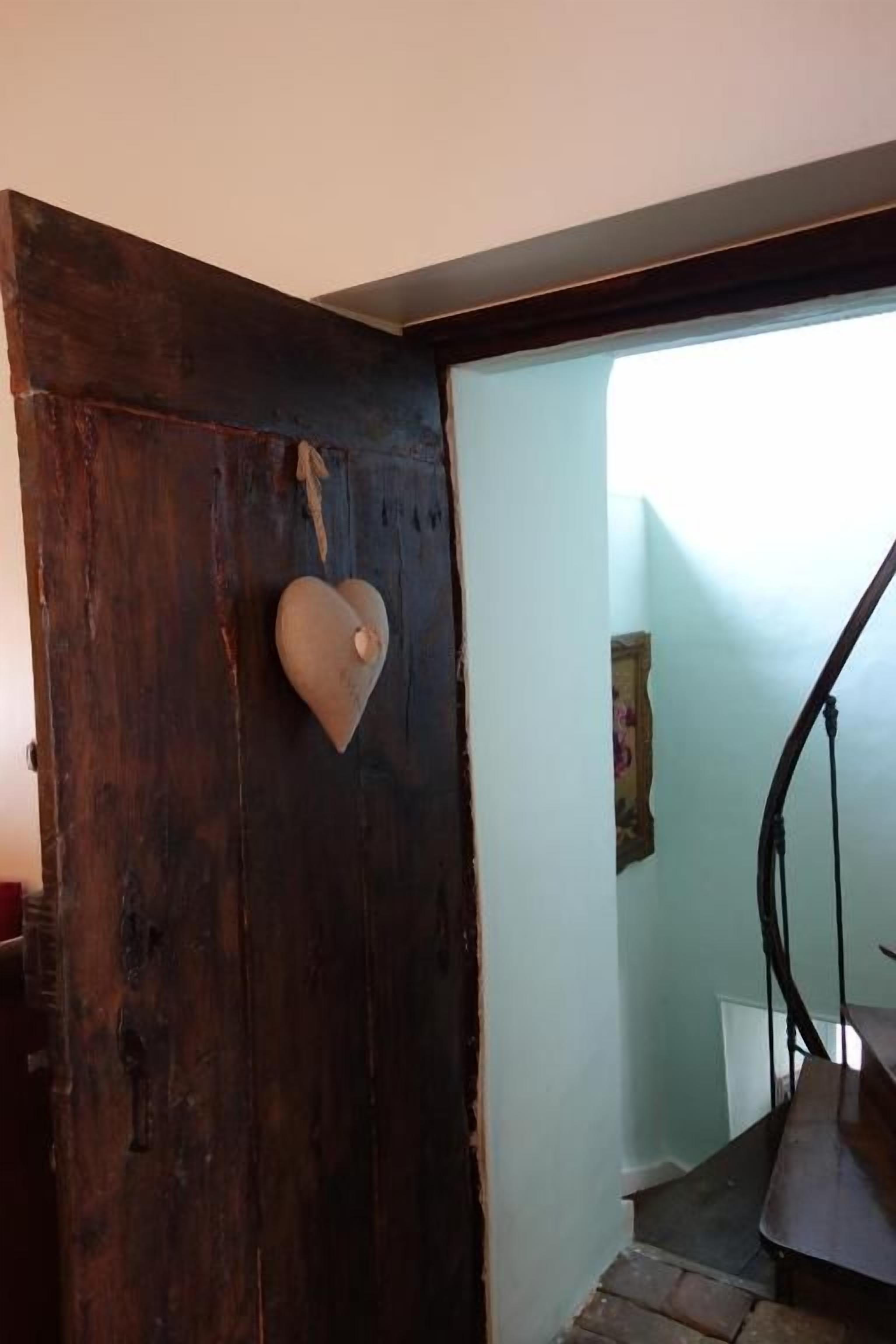 A wooden door with a heart-shaped decoration, leading to a staircase with a metal railing.