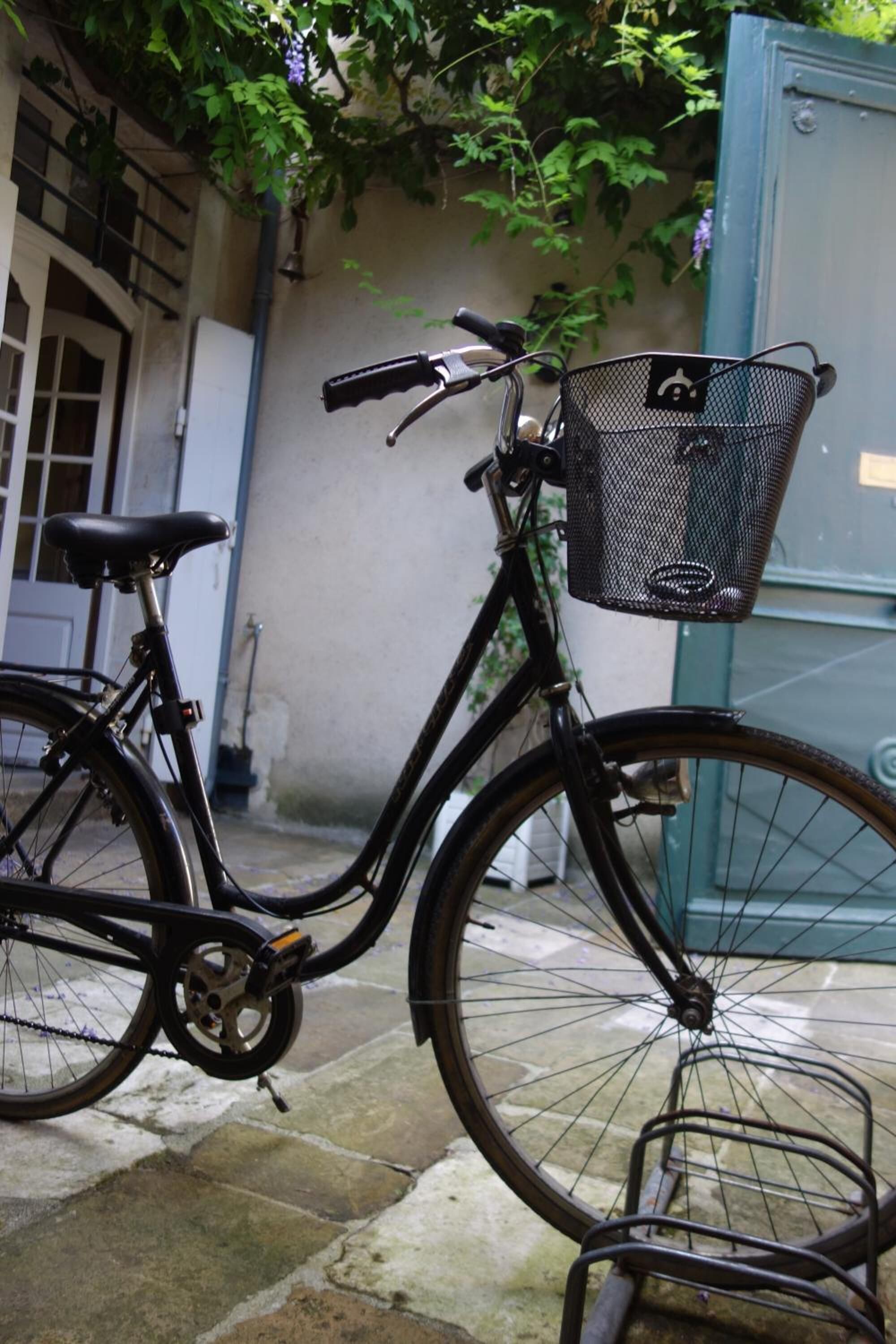 Una bicicleta estática con una canasta, estacionada sobre un pavimento de piedra.