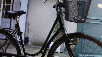 Una bicicleta estática con una canasta, estacionada sobre un pavimento de piedra.