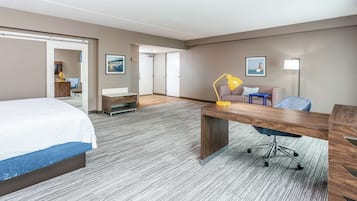 Una habitación de hotel con una cama, un escritorio, una silla, una lámpara y un sofá.