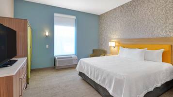 Une chambre d’hôtel avec un lit, un bureau, une télévision et une fenêtre avec des rideaux.