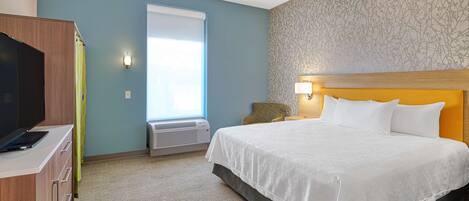 A hotel room with a bed, a desk, a television, and a window with curtains.