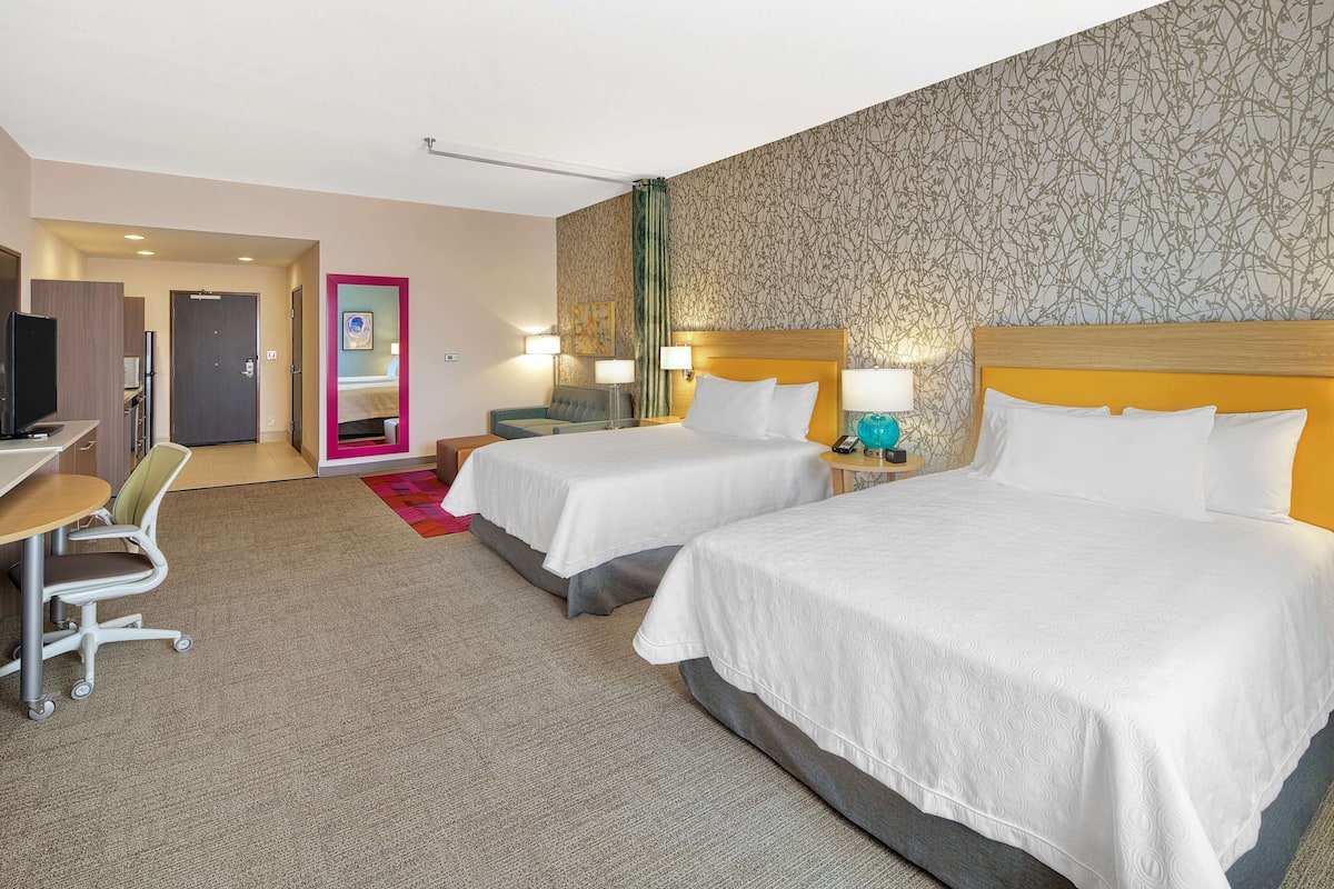 Une chambre d’hôtel avec deux lits, un bureau, une chaise et un téléviseur.