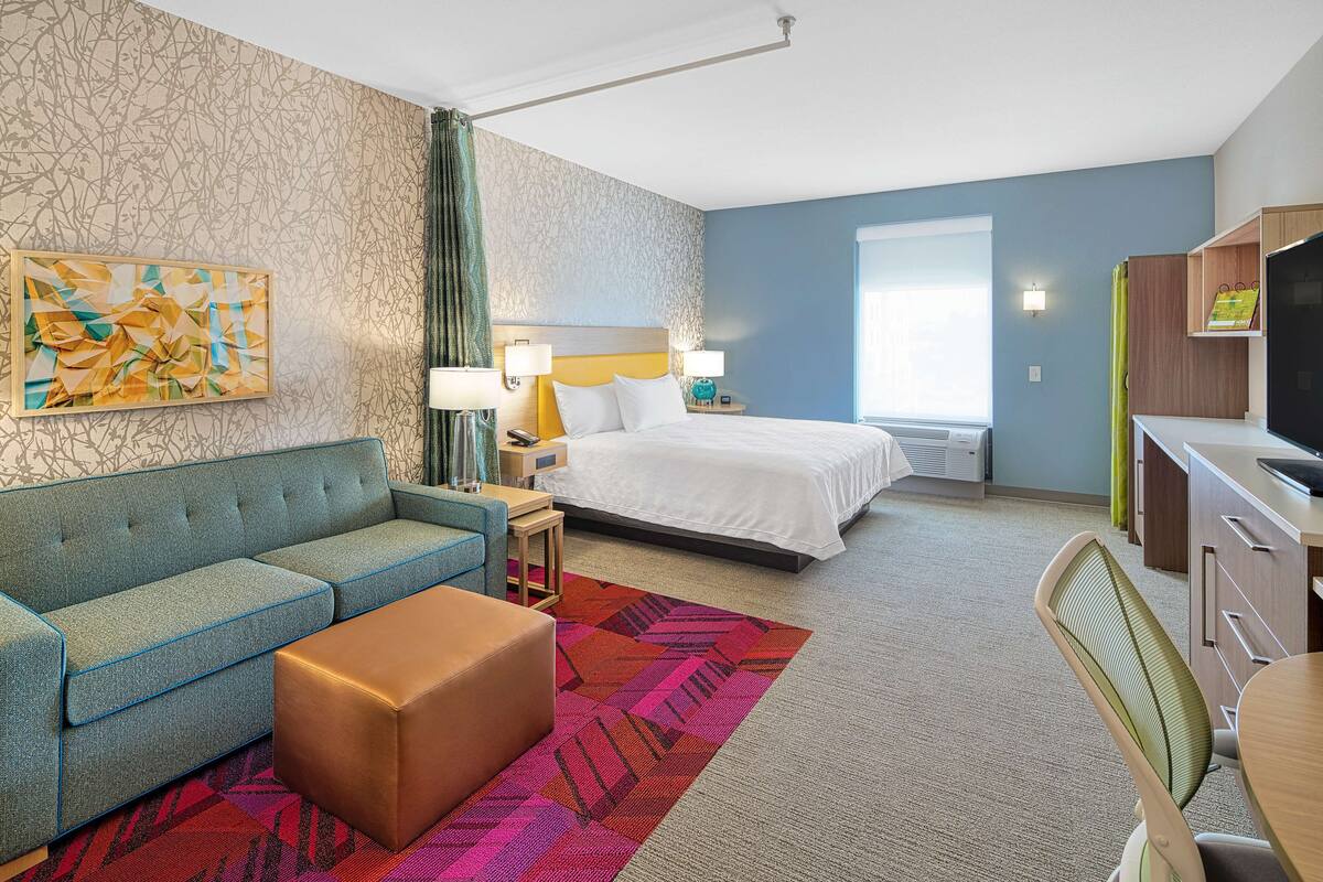 Une chambre d’hôtel avec un lit, un canapé, un bureau et une télévision.