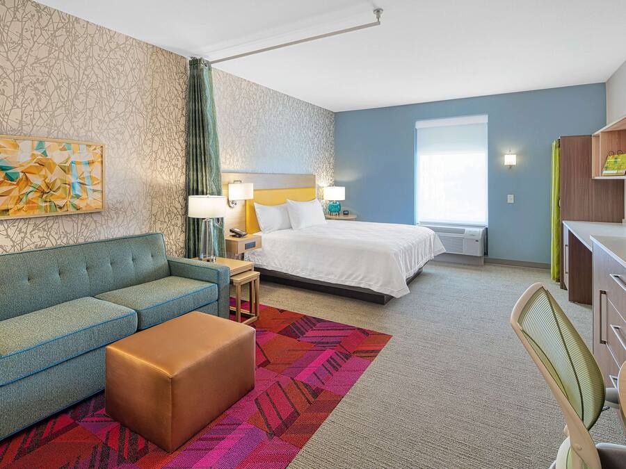 Una habitación de hotel con cama, sofá, escritorio y televisión.