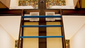 Una cama litera con escalera, cabecera de madera y pared con estampado.