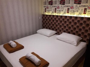 A hotel room with a bed, two pillows, and two rolled towels. - FixOn Capsule Hotel (Purwokerto)