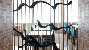 Una habitación con pared de ladrillo, barandilla de madera y zona de comedor con sillas azules y una mesa.