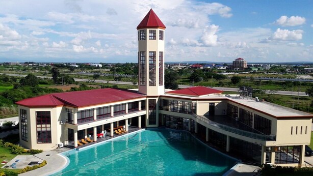 A hotel with a swimming pool, a tower, and a view of the surrounding landscape. - Rose Land Apartment Hotel (Naypyidaw)