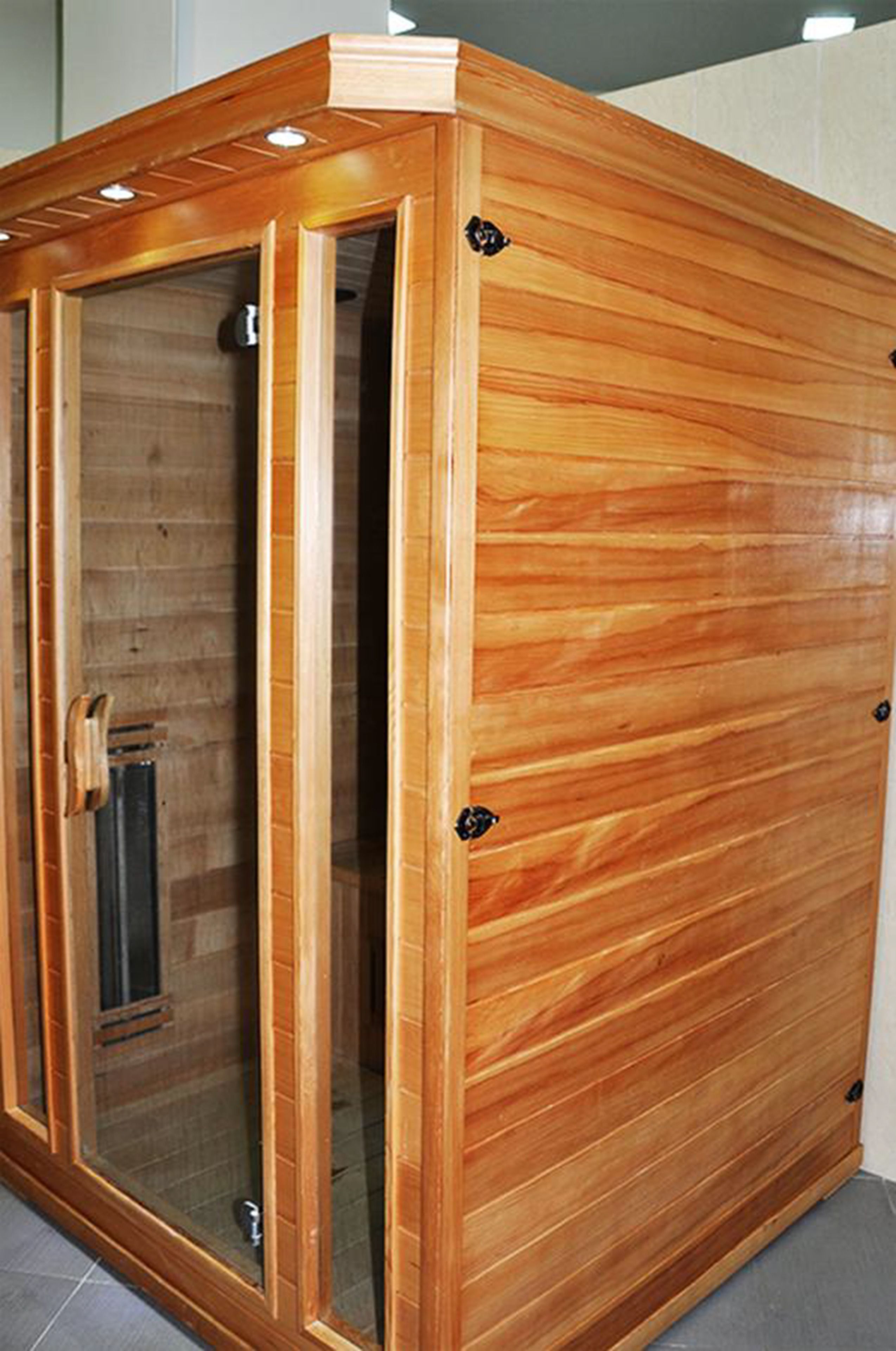 Un sauna en bois doté d’une porte en verre et d’une poignée en métal.
