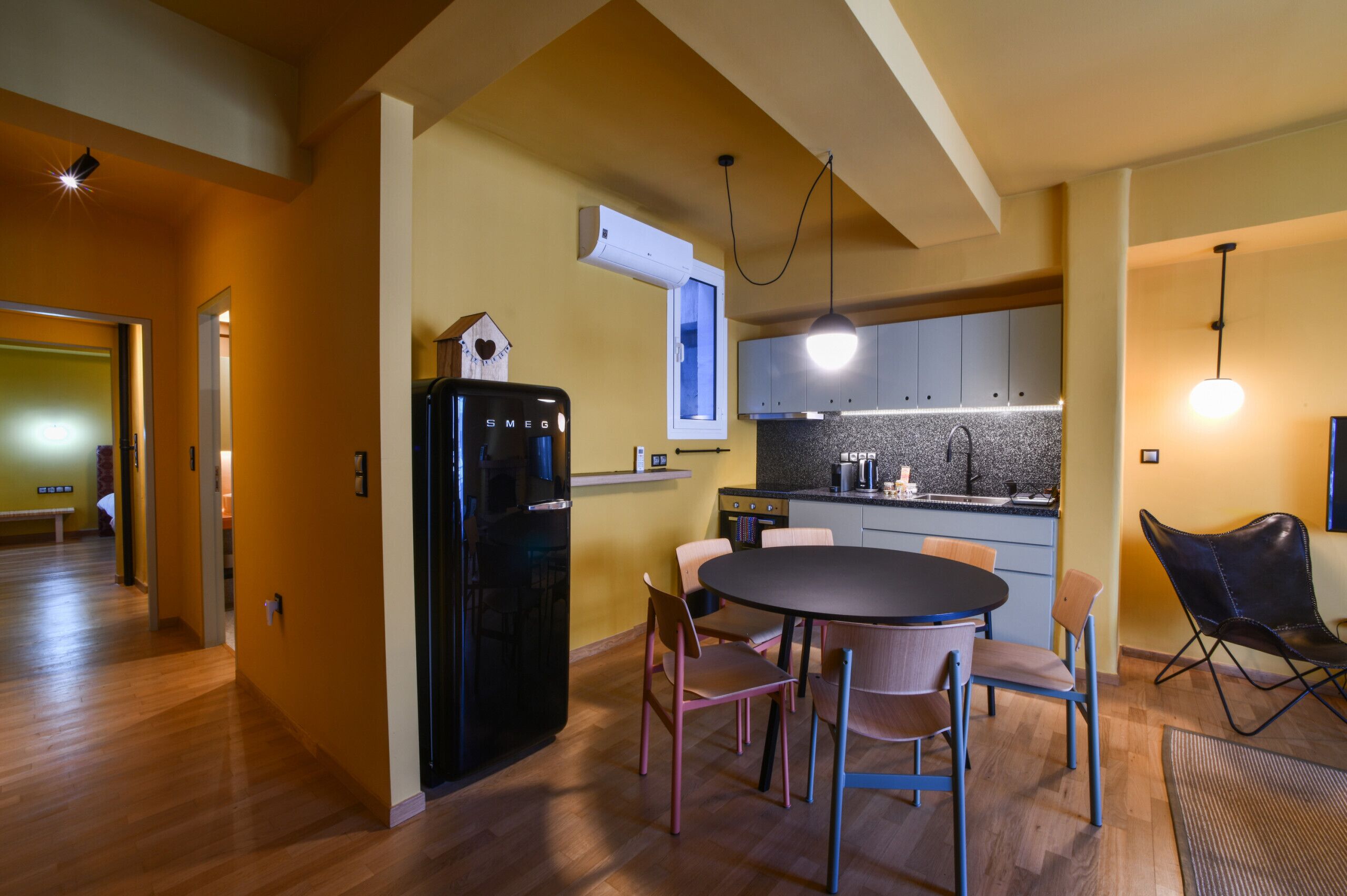 A compact kitchen with a refrigerator, dining table, and chairs.