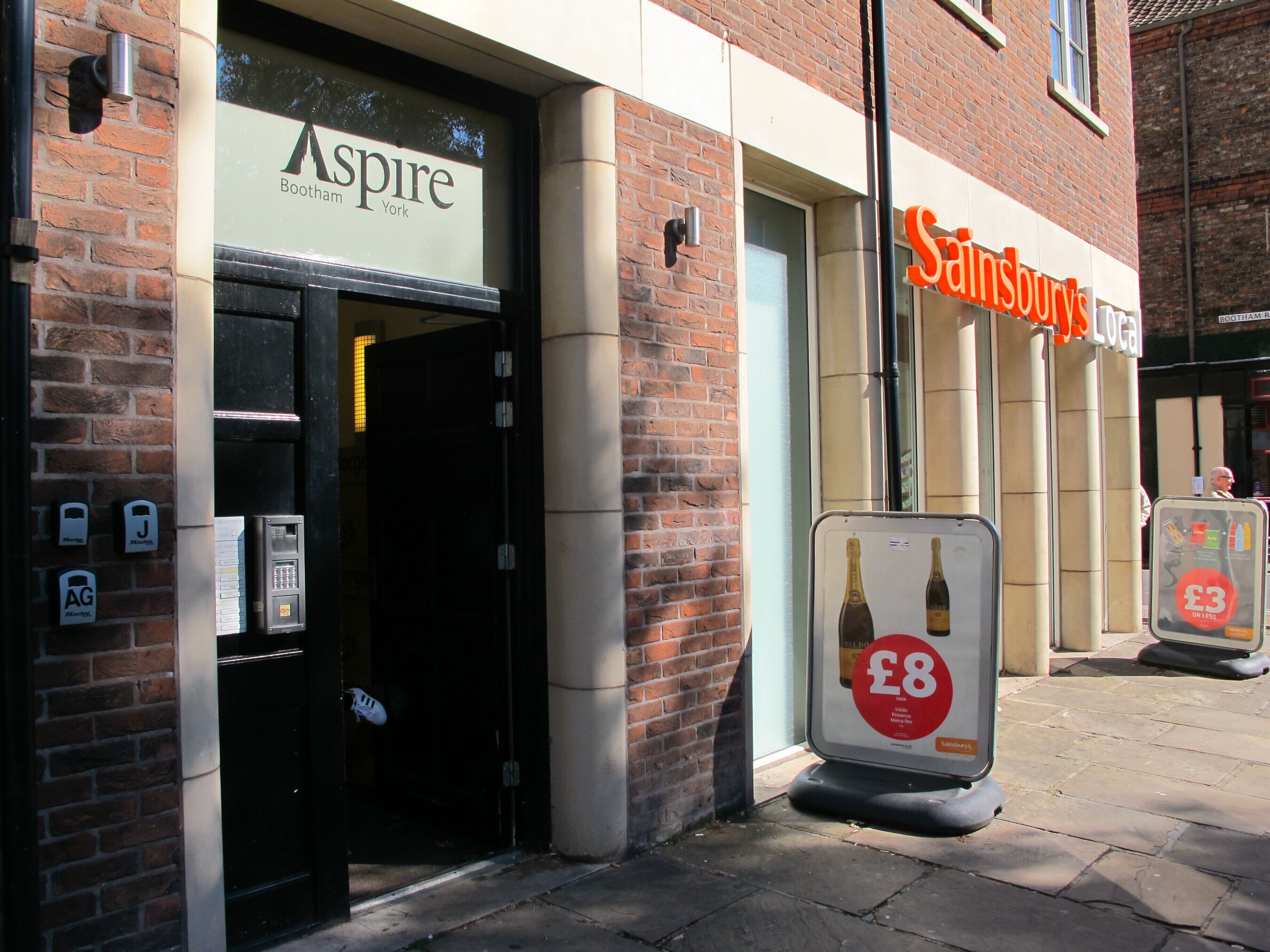 A storefront with a sign for 'Aspire' and 'Sainsburys Local'.
