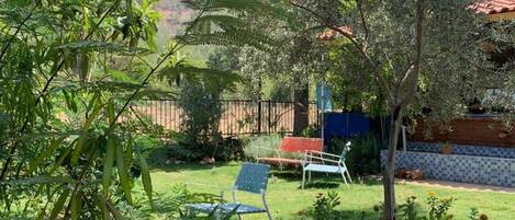 A garden with a lawn, a bench, and a building with a tiled roof.