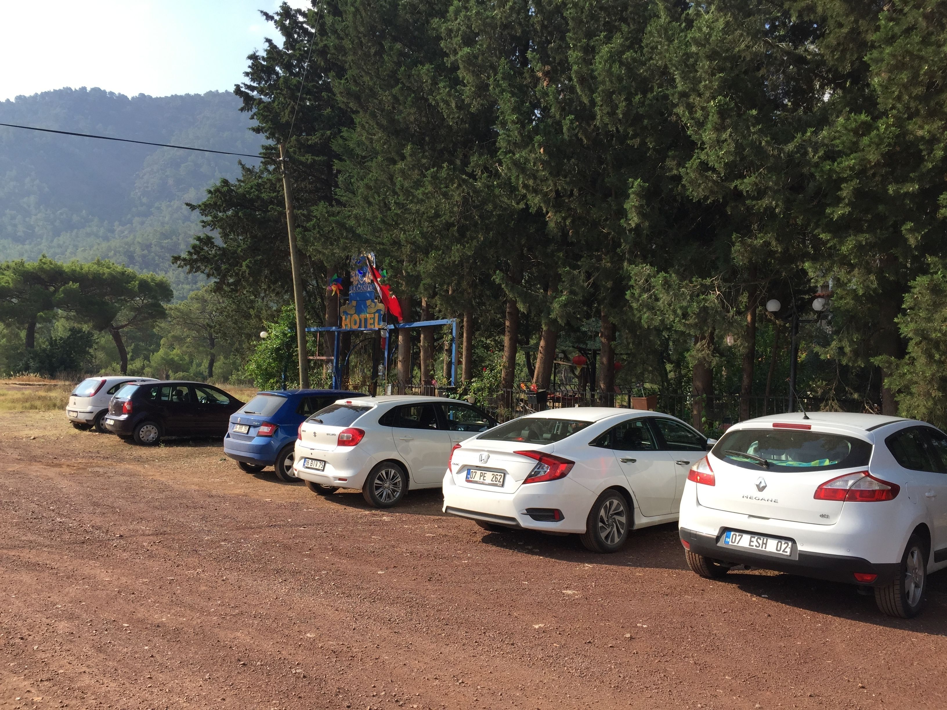 A row of parked cars in a parking lot with a hotel sign in the background.