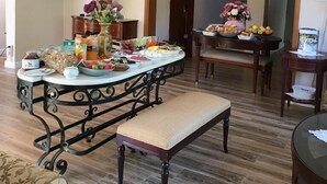 Un comedor con una mesa redonda dispuesta para una comida, un televisor montado en la pared y un arco que conduce a otra habitación.