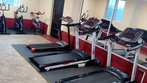 A gym with treadmills, stationary bikes, and a mirrored wall. - JLW Hostel (Berekuso)