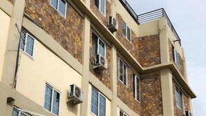 A multi-story building with stone facade and multiple air conditioning units. - JLW Hostel (Berekuso)