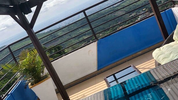 A balcony with a view of a cityscape, a pool, and a blue and white color scheme. - JLW Hostel (Berekuso)