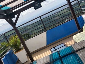 Un balcón con vistas a un paisaje urbano, una piscina y una decoración en blanco y azul.