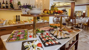 Een buffet met diverse gerechten, zoals salades, vleeswaren en fruit.