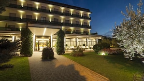 Een meerlaags hotel met een goed verlichte ingang, verharde paden en aangelegde tuinen.