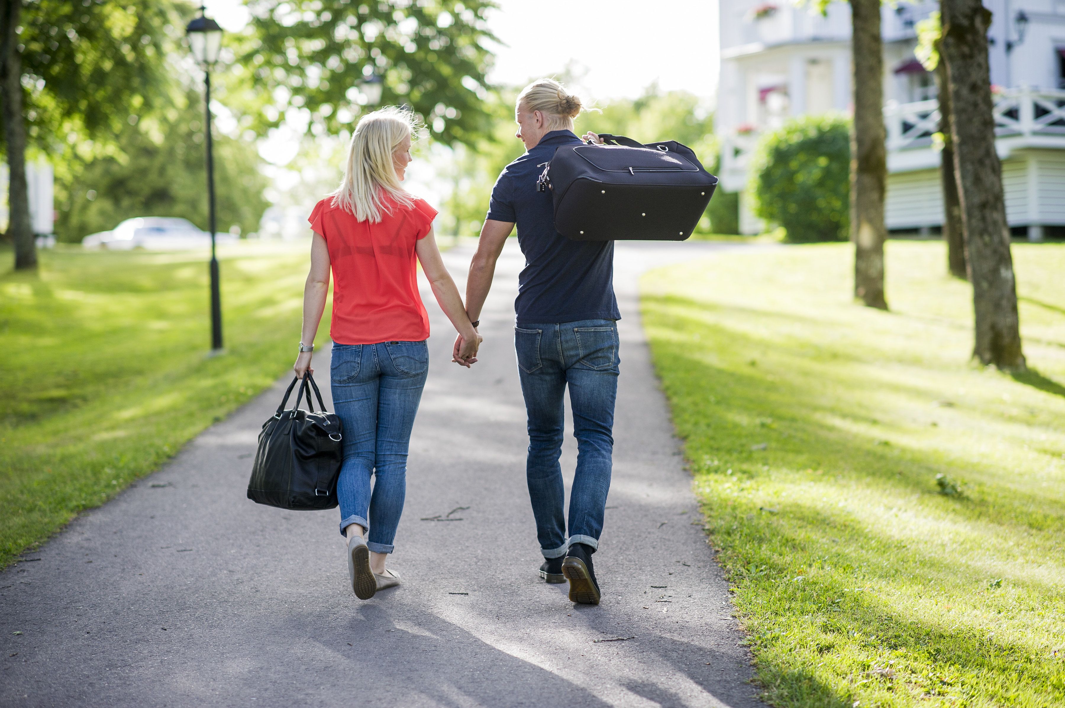 Two people walking on a paved path in a park-like setting.