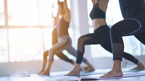 A yoga class in a bright room with large windows.
