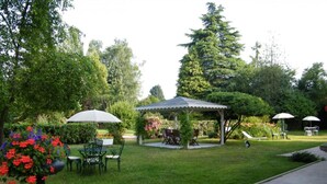 A garden patio with outdoor seating, a gazebo, and a variety of plants. - Villa des Iris (Saint-Felix)