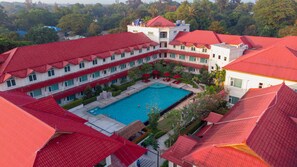 A hotel with multiple red-roofed buildings, a central swimming pool, and lush greenery surrounding the property. - Hotel Dawei (Dawei)