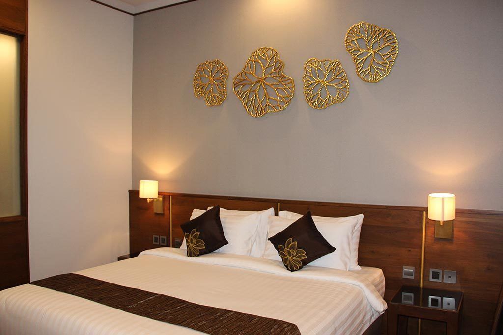 A hotel room with a large bed, two bedside lamps, and decorative wall art.