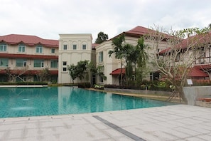 A swimming pool surrounded by buildings with red roofs and a clear blue sky.