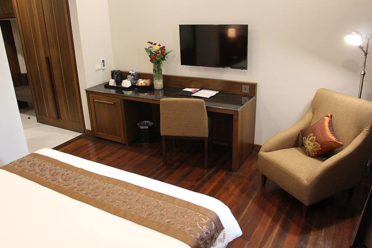 Ein Hotelzimmer mit Bett, Schreibtisch mit Stuhl, Fernseher und Lampe.