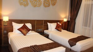 A hotel room with two beds, a wooden headboard, wall art, and a window with curtains. - Hotel Dawei (Dawei)