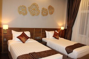 A hotel room with two beds, a wooden headboard, wall art, and a window with curtains. - Hotel Dawei (Dawei)
