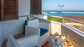 A balcony with wicker furniture, a small table with breakfast items, and a view of the sea. - 100 Passi Dal Mare (Agropoli)