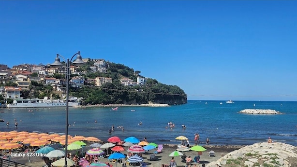 A coastal town with a beach, colorful umbrellas, and boats in the water. - 100 Passi Dal Mare (Agropoli)