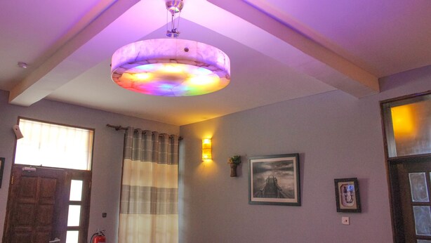 Ein Zimmer mit Deckenventilator, einem Vorhangfenster, einer Tür und einer Wandleuchte.