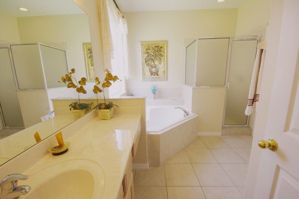 A bathroom with a large mirror, a sink, a bathtub, and a shower.