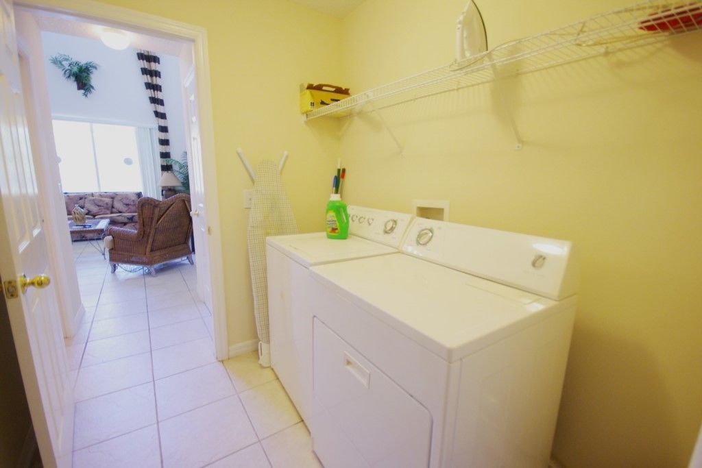 A laundry area with a washing machine, a drying rack, and a shelf with items.