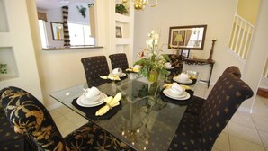 A dining area with a glass table, chairs with a floral pattern, a chandelier, and a mirror on the wall. - Ly53792 - Emerald Island - 6 Bed 5 Baths Villa (Kissimmee)
