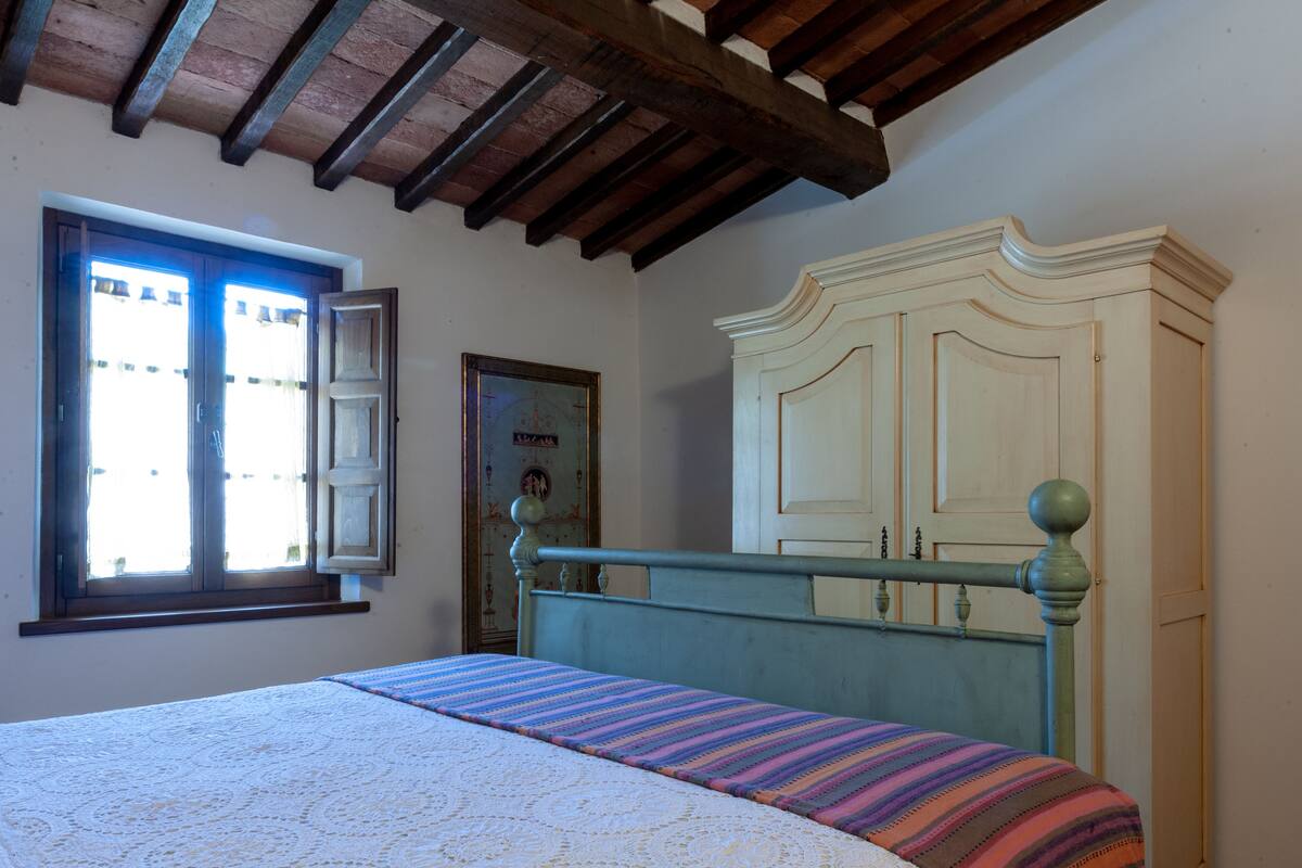 Ein Schlafzimmer mit Bett, Schrank, Fenster und Tür.