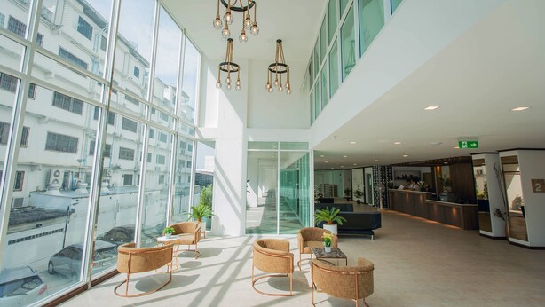 Un hall d’hôtel moderne doté de grandes baies vitrées, d’un comptoir d’accueil et d’espaces aménagés avec des sièges.