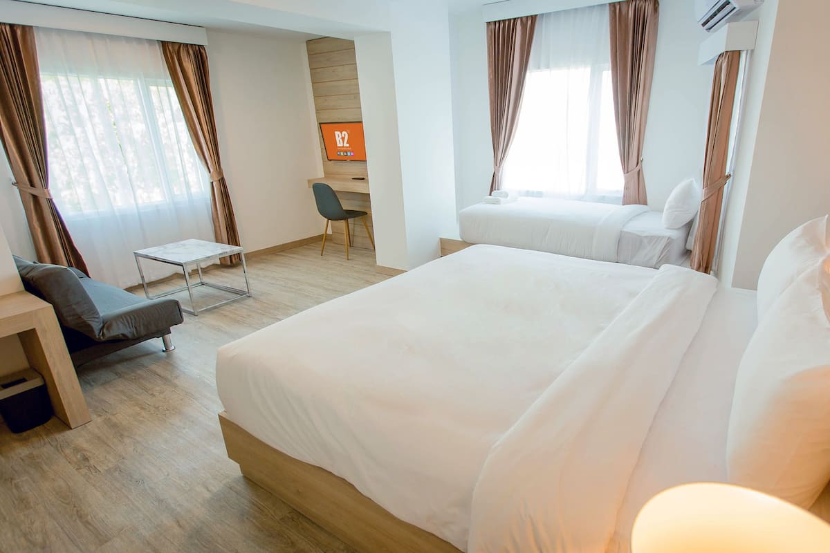 A hotel room with a large bed, a desk, a chair, and a TV on the wall.