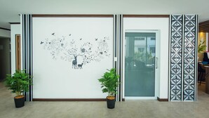 Une pièce dotée d’un grand mur décoratif représentant un arbre et des cerfs, d’une porte-fenêtre coulissante et d’une cloison à motifs.