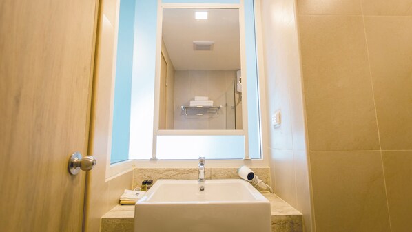 Un baño con un lavamanos blanco, un espejo y un perchero para toallas.