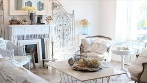 A room with a fireplace, white furniture, and a view through large windows. - Masseria Cappuccini (Ostuni)