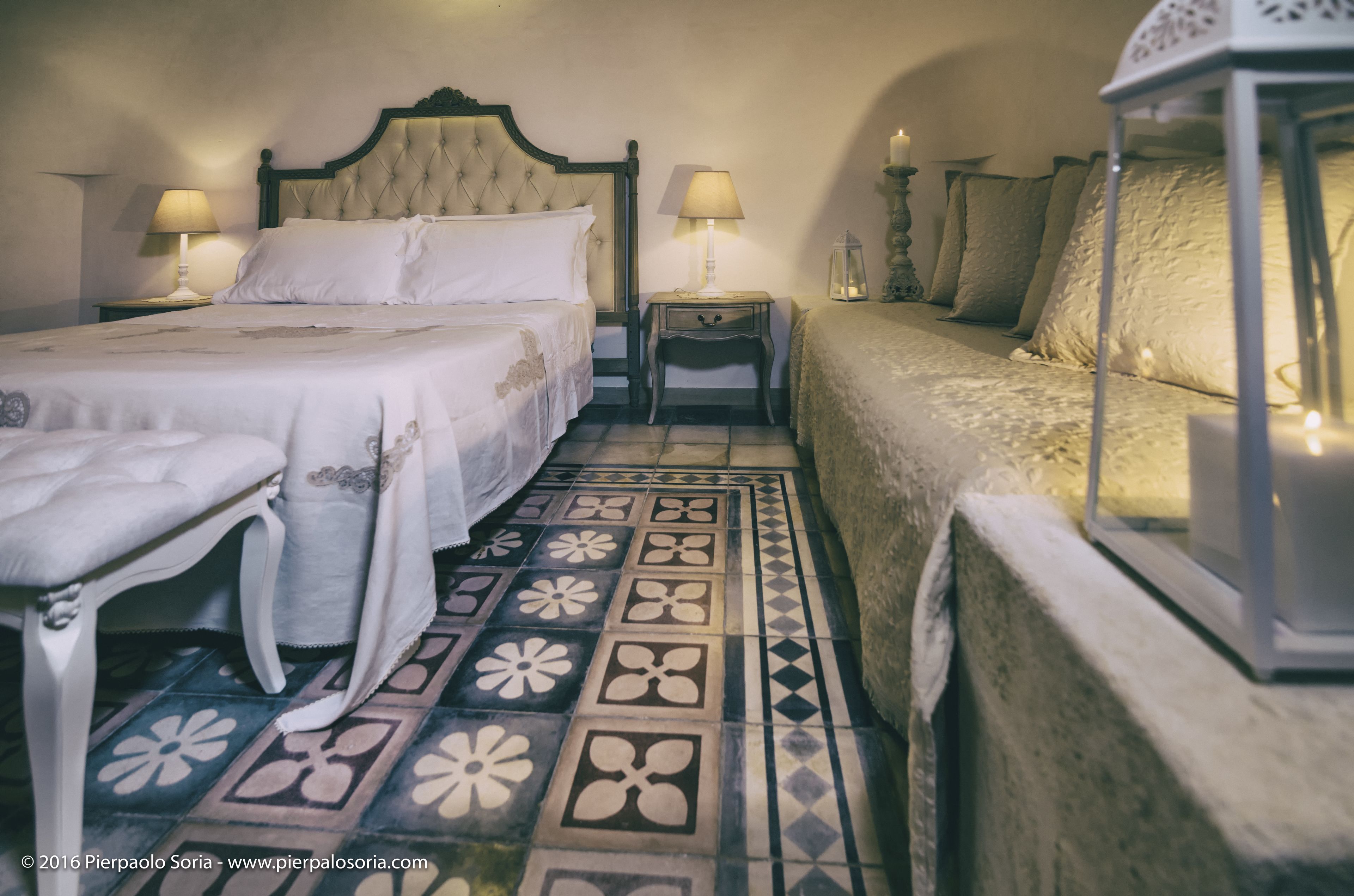 A traditional bedroom with a bed, bedside tables, a nightstand, a lamp, and a lantern.